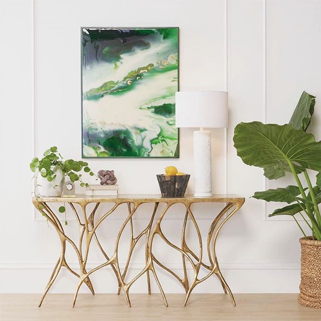 Stylish entryway featuring a gold sculptural console table, green abstract wall art, and plants in interior design, including decorative indoor greenery.