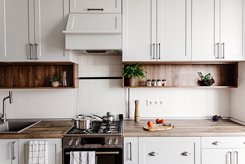 Warm white kitchen with natural wood shelving and neutral tile backsplash — timeless, inviting design trend for 2026.